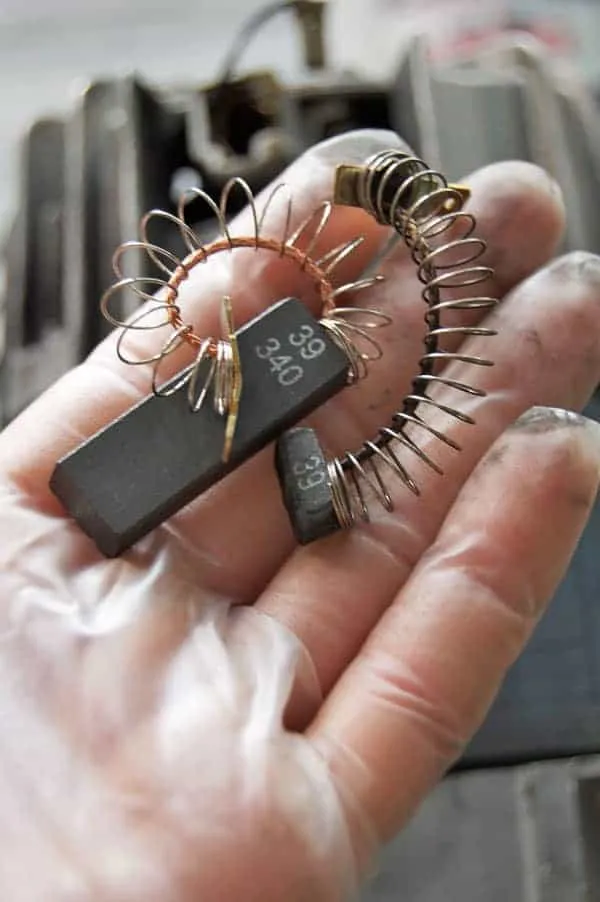 Several carbon motor brushes held in a person's hand
