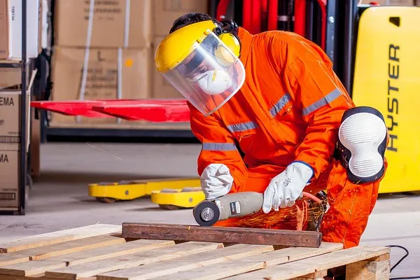 Worker wearing face protection while handling a grinder