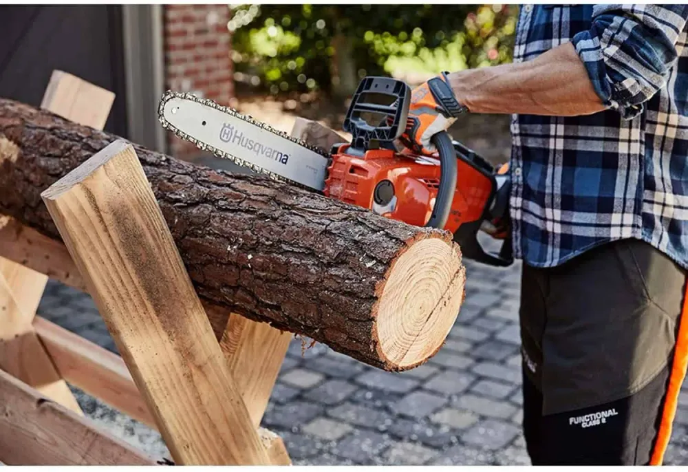 Cordless chainsaw cutting a log on a sawhorse