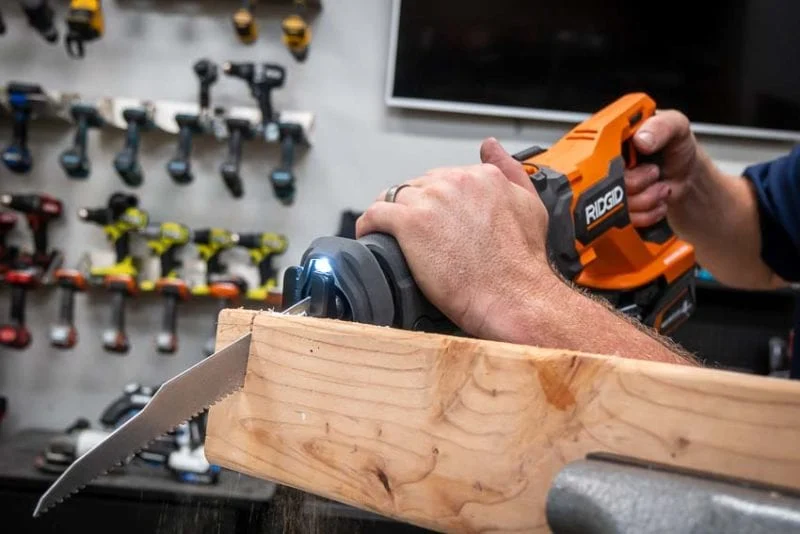 Compact reciprocating saw cutting through a timber beam