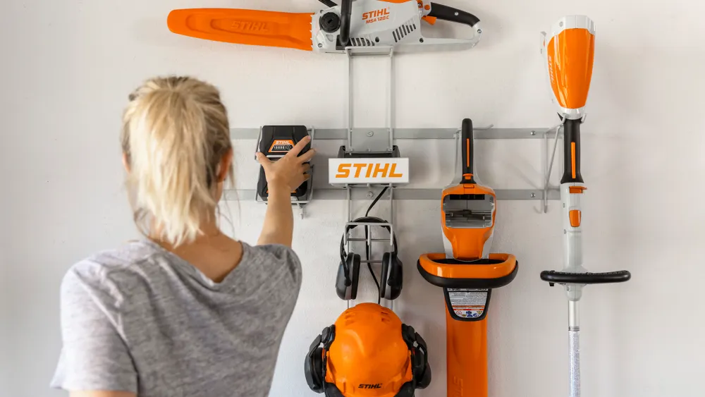Cordless garden tools organized on a garage wall