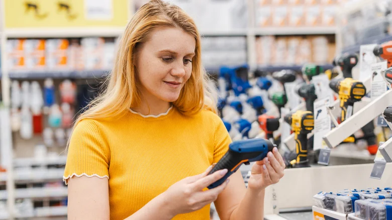 Customer comparing compact fastening tools in a store
