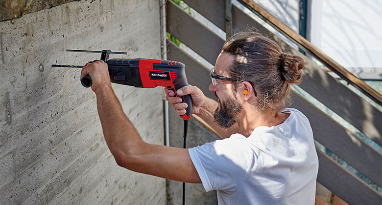 Operator holding a drill against a concrete wall