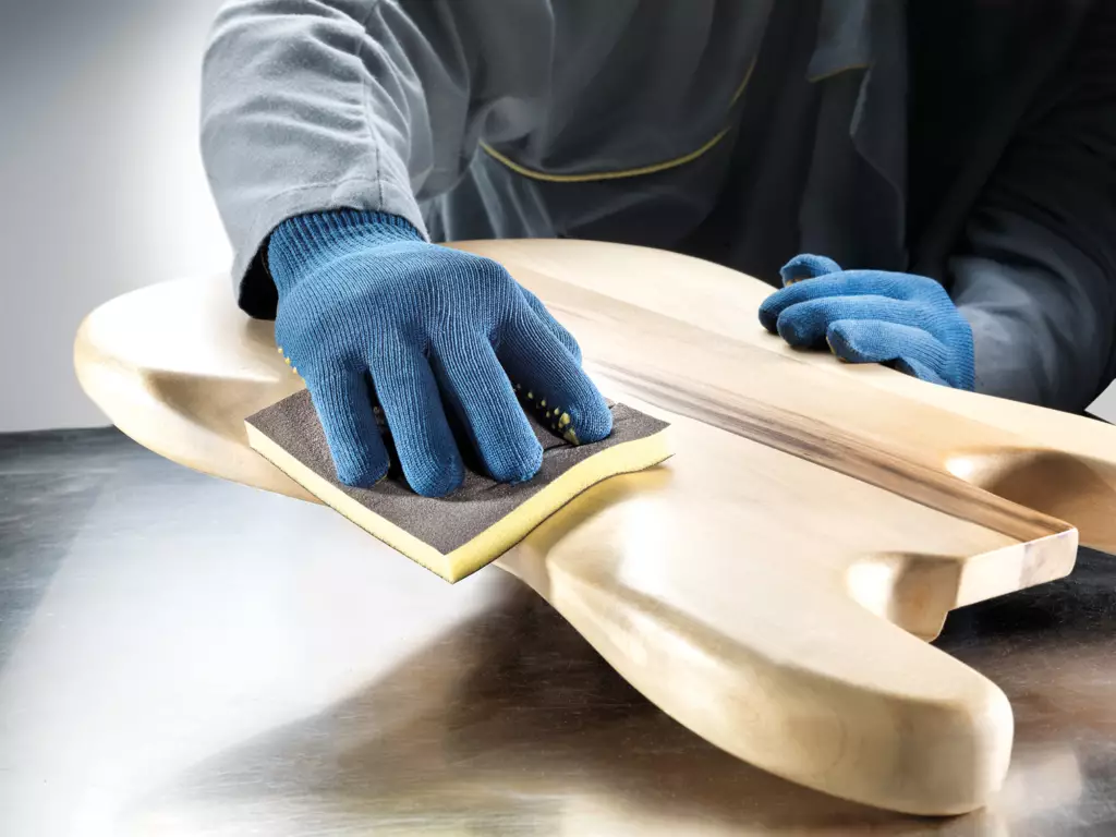 Hand sanding a curved wooden piece