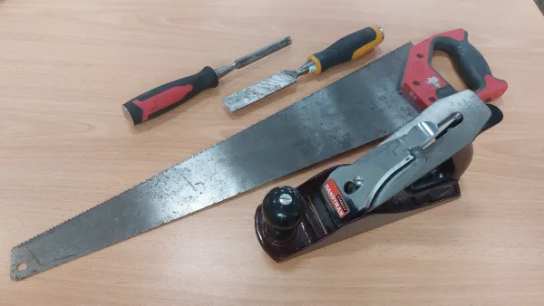Hand saw and compact power saw arranged on a workbench
