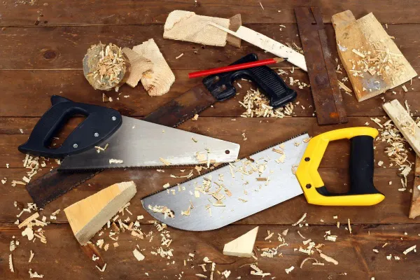 Several hand saws and wood offcuts on a workshop bench