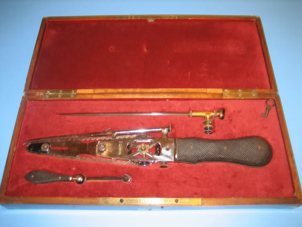 Historic chainsaw instrument displayed in a red case