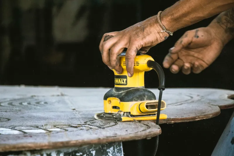 Palm-sized sander working on a round tabletop