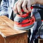 Craftsman random-orbit sander smoothing a wooden board