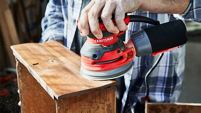 Craftsman random-orbit sander smoothing a wooden board