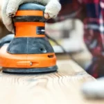 Random orbit sander smoothing a wooden surface