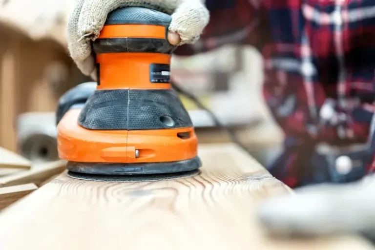 Random orbit sander smoothing a wooden surface