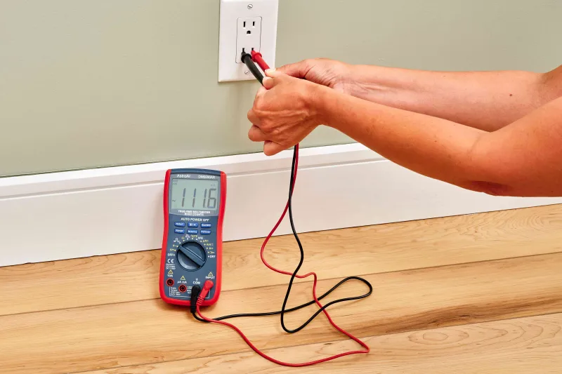Digital multimeter testing the voltage of a wall outlet