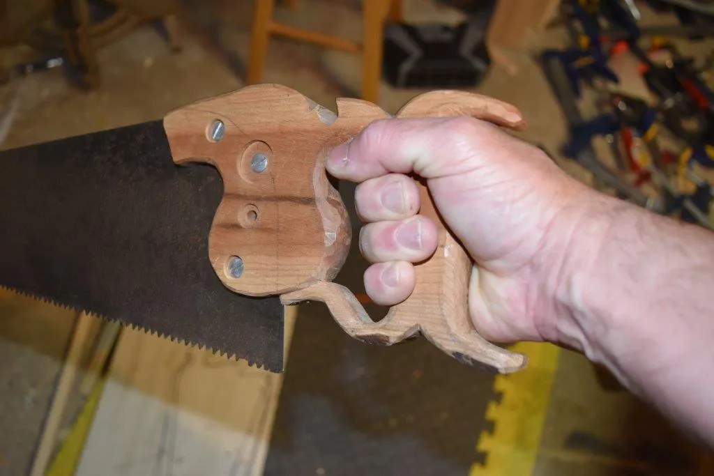 Carpenter holding a traditional wooden-handle hand saw